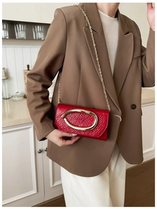 Detail of a red textured leather small square bag with a gold metal ring and chain