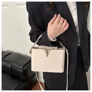 Dettaglio borsa a tracolla in pelle beige con fibbia a V dorata e tracolla sottile