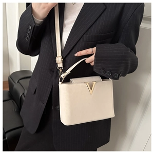Detail of cream structured handbag with gold V-clasp on a black pinstripe suit