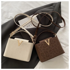 Dettaglio di borse beige e leopardate con accessori metallici a forma di V dorati