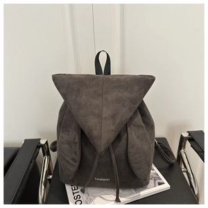 Detail of grey suede backpack with triangle flap, ear accents, and fashion branding