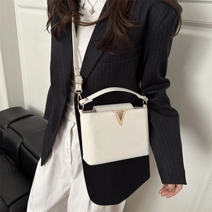 White leather handbag with gold V-logo shown in cross-body style on a model