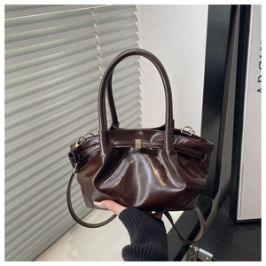 Detail of dark brown ruched bucket bag showing glossy faux leather and gold metal buckle