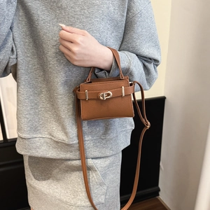 Mini sac Kelly chic en cuir marron avec boucle dorée porté par un mannequin