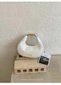 Détail du sac hobo en cuir blanc avec boucle en métal doré sur pierre