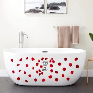 Detail view of red rose petals and All You Need Is Love quote sticker on white bathtub