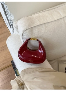 Détail du sac hobo croissant en cuir verni bordeaux avec boucle dorée et logo