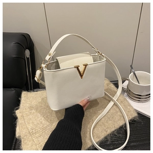 Detailed view of the white leather bucket bag with a golden V buckle and adjustable strap
