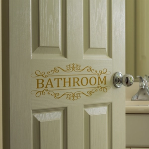 Sticker mural doré pour salle de bain avec motifs vintage sur une porte en bois blanc