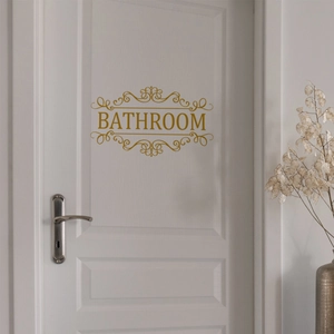 Détail d'un sticker doré de salle de bain avec motifs floraux sur une porte blanche