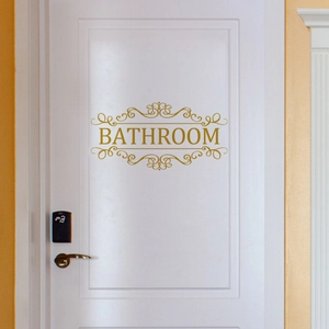 Sticker mural de salle de bain doré avec volutes décoratives sur une porte blanche