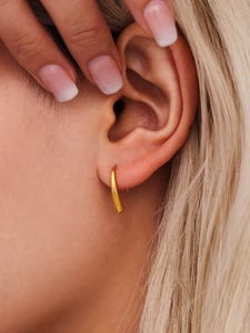 Close-up of minimalist teardrop gold earrings worn by a model with a polished finish