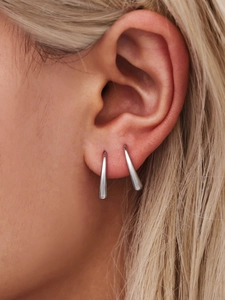 Close-up of silver teardrop hook earrings worn by a model to show elegant scale and luster