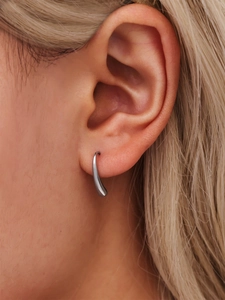 Close-up of polished silver teardrop earrings on model showing minimalist curved design