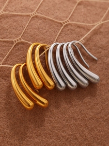 Macro shot of minimalist teardrop earrings in polished gold and silver finishes