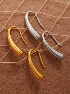 Detail of teardrop hook earrings in gold and silver hanging on lace texture