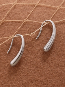 Macro shot of minimalist silver teardrop earrings with polished stainless steel finish