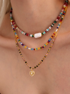 Detailed view of triple-layered colorful stone beaded necklace with a gold heart pendant