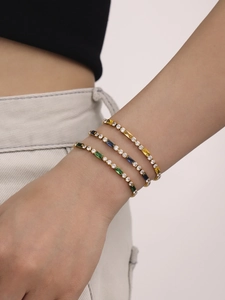 Detail of three tennis bracelets featuring colorful zircon stones in gold finish
