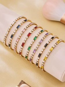 Close-up of eight multicolored baguette zircon tennis bracelets on a white display stand