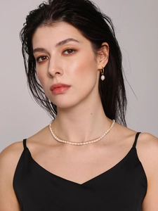 Detail of freshwater pearl necklace and gold hoop earrings on model for a chic style