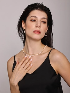 Detail of freshwater pearl necklace and gold hoop earrings set on model neck