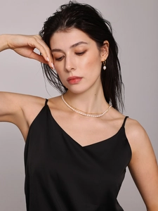 Detail of elegant double-layer freshwater pearl necklace and gold earrings on a model