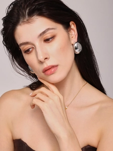 Polierte silberne Bohnenohrringe und goldene Halskette mit Würfelanhänger am Model