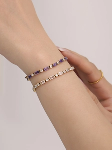 Dettaglio di bracciali tennis dorati con zirconi colorati rettangolari sul polso
