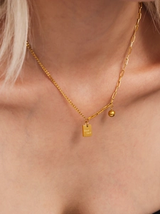 Dettaglio della collana placcata oro con targhetta Good Luck e pendente a sfera