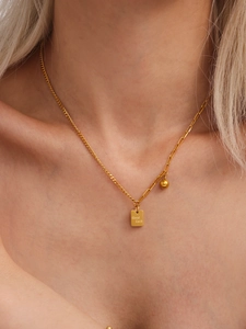 Dettaglio della collana in acciaio al titanio dorato con ciondolo Good Luck sul modello