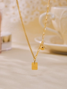 Dettaglio della collana asimmetrica dorata con pendente quadrato Good Luck