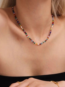 Close-up of vibrant colorful beaded necklace with pearls and gold accents on model