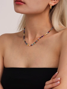 Detail of bohemian necklace with colorful crystal beads and faux white pearls on a model