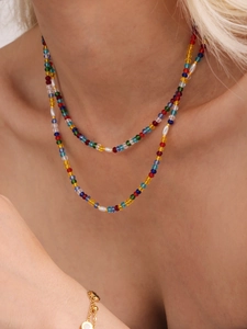 Close-up of colorful crystal bead necklace with white pearls on female neck
