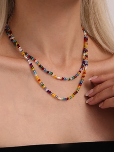 Close-up of double-layer necklace with colorful crystal beads and faux pearls on model