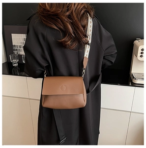 Detail of caramel crossbody bag with a patterned jacquard wide strap and gold hardware