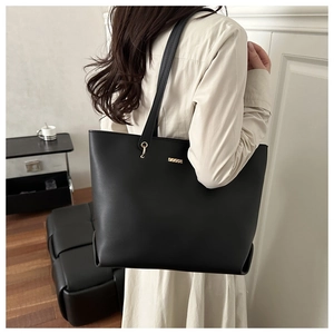 Close-up of minimalist black matte tote bag with elegant gold bar metal detail