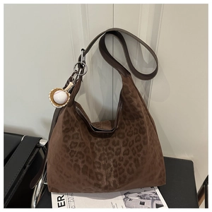 Close-up of leopard print tote bag with brown leather strap and baseball glove charm