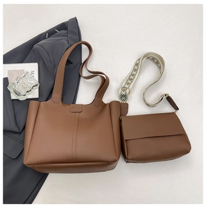 Brown leather tote and crossbody bag with Bohemian embroidered strap on white background