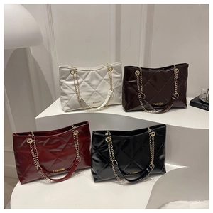 Détail de quatre sacs matelassés en blanc, marron, rouge et noir sur un présentoir