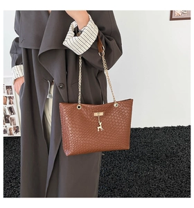 Detail of woven texture on brown bucket bag with gold deer charm and chain strap