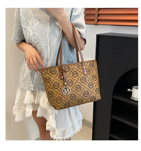 Détail d'un grand sac cabas marron avec imprimé M et pendentif logo rond métallique