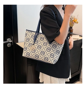 Gros plan du sac cabas affichant l'imprimé lettres M et le pendentif doré chic