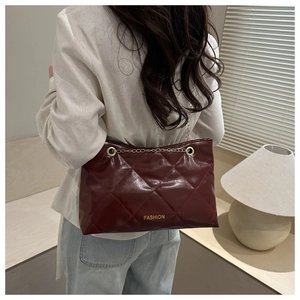 Détail du sac fourre-tout matelassé bordeaux avec lettrage doré et chaîne