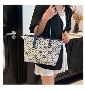 Détail du sac cabas imprimé avec motif logo M bleu et pendentif métallique sur la lanière