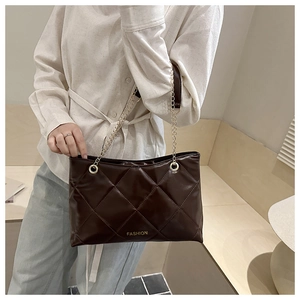Détail d'un sac cabas marron foncé matelassé avec des bandoulières en chaîne dorée