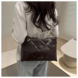 Détail d'un sac cabas matelassé marron foncé avec chaîne dorée et logo FASHION gravé