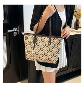 Détail du sac cabas élégant avec pendentif M doré et bandoulières en cuir souple