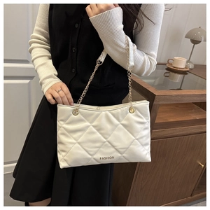 Gros plan sur un sac cabas matelassé blanc avec bandoulière chaîne dorée porté par mannequin